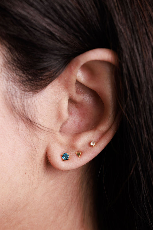 Blue topaz stud earrings stacked with a triangle stud and white topaz stud earring