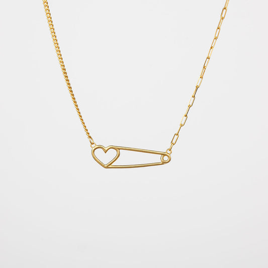 A gold-colored heart pin necklace with a curb chain on one side and a paperclip chain on the other side