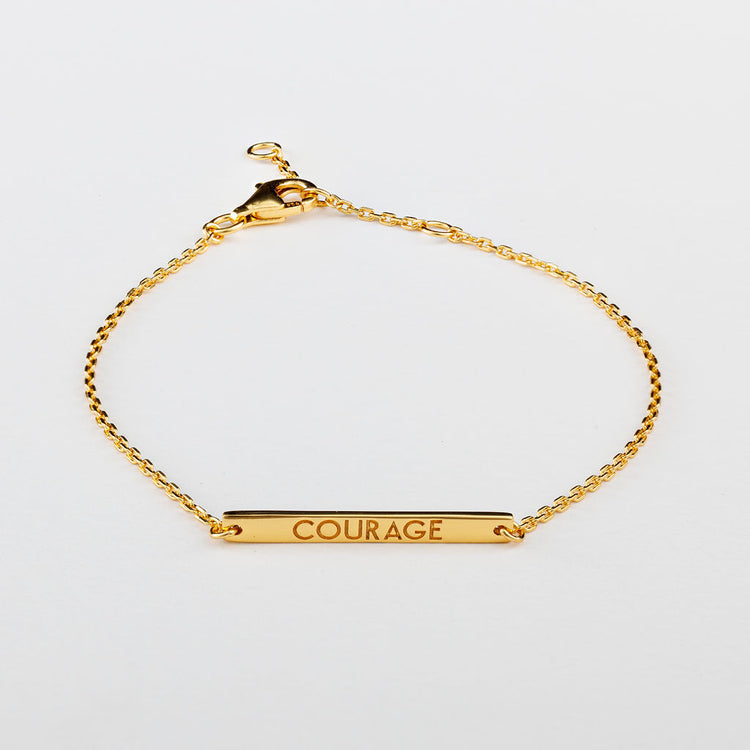 A gold bracelet with the word 'COURAGE' written in capital letters, featuring a lobster clasp closure.