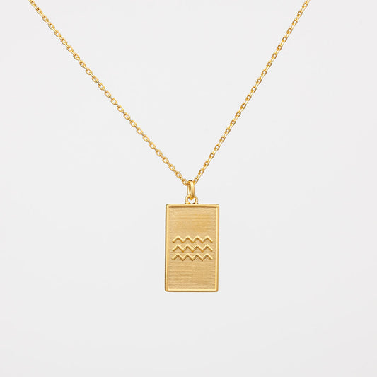 A gold vermeil necklace with a rectangular pendant featuring wave motifs.