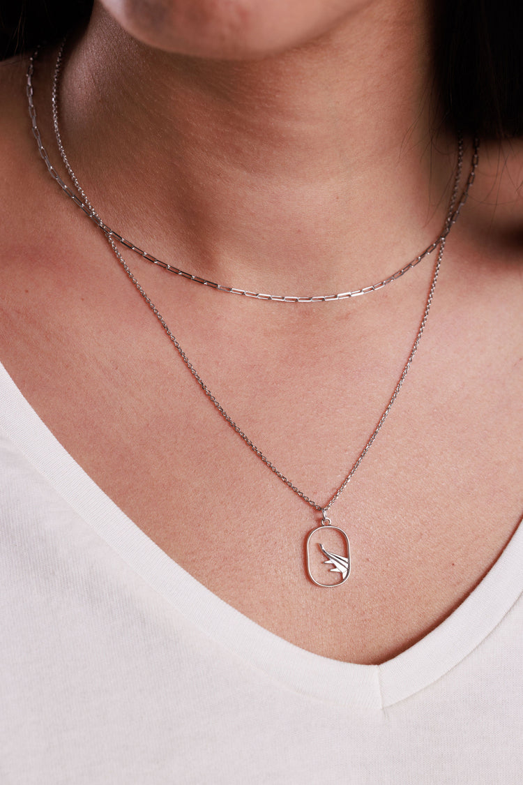 Silver paperclip chain paired with an airplane necklace in sterling silver