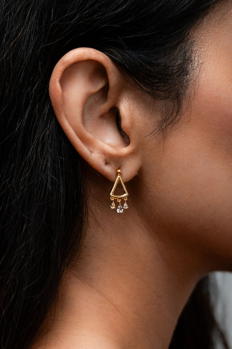 Minimal gold earring with three small white topaz drops hanging from the lower arc.