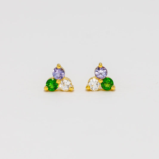A pair of gold vermeil stud earrings featuring trillion-shaped gemstones, each with one purple gemstone, green gemstone, and white gemstone