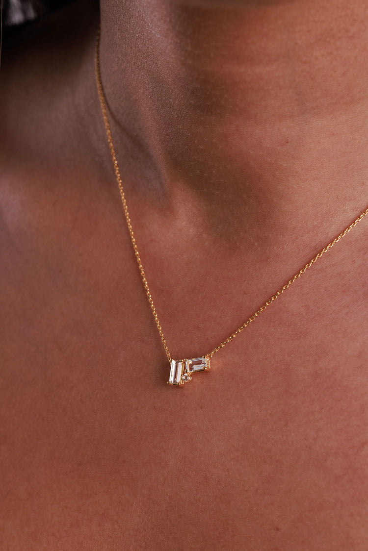 White topaz cluster necklace with baguette and round gemstones on a gold chain