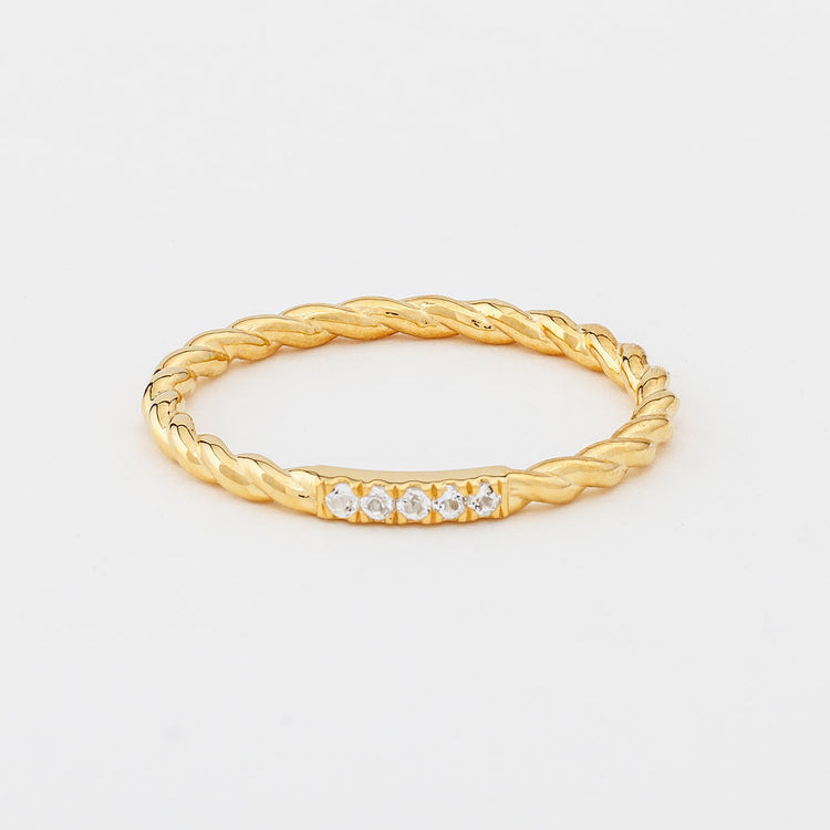 A gold twisted band ring with white topaz gemstones, presented against a white background.