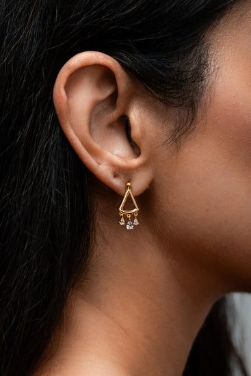 Minimal gold earring with three small white topaz drops hanging from the lower arc.