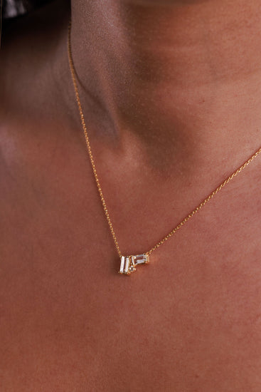 White topaz cluster necklace with baguette and round gemstones on a gold chain